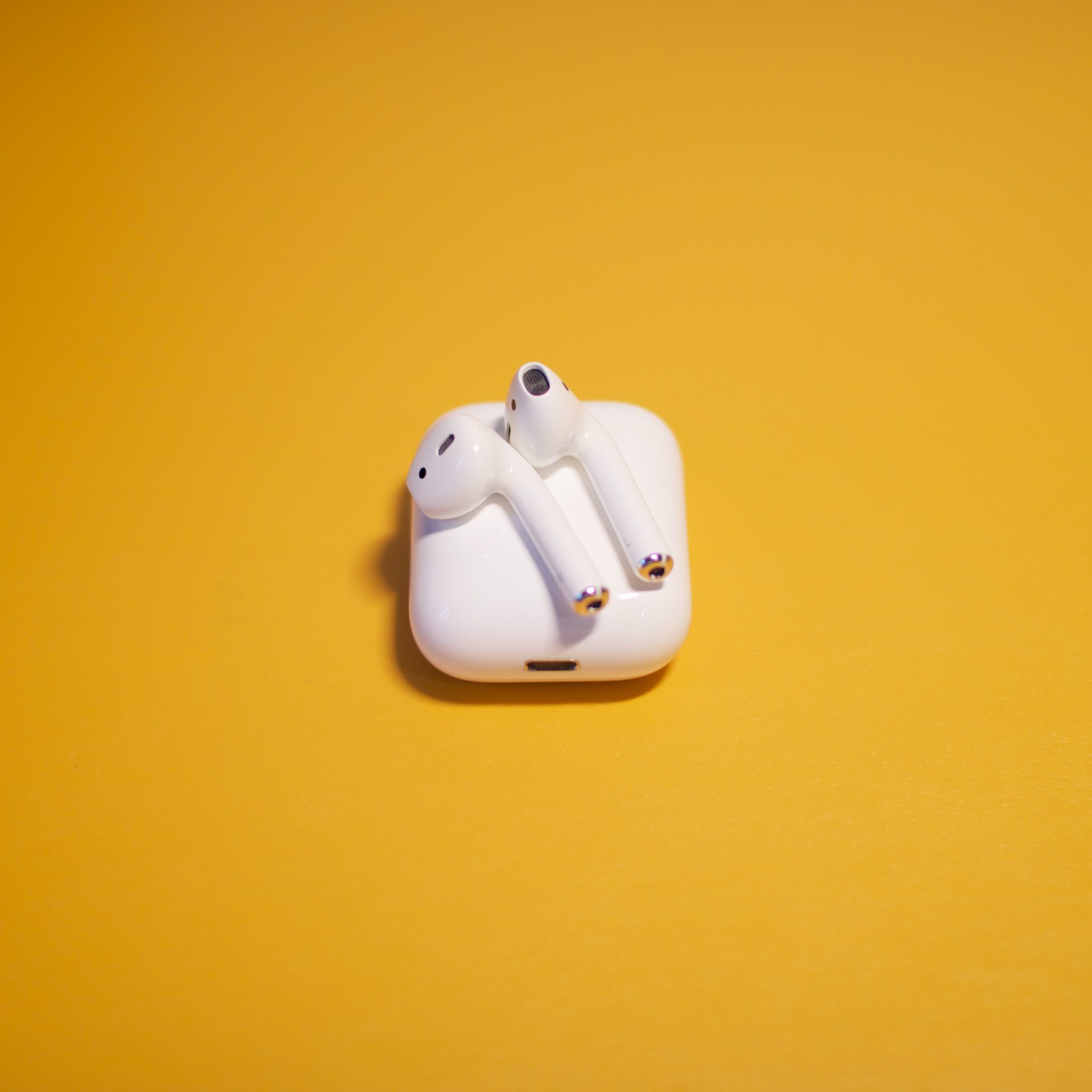 AirPods 2 on case with yellow background