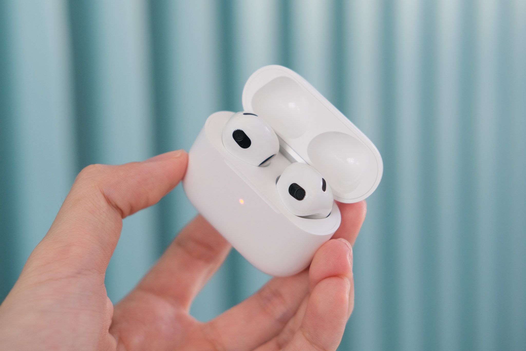 Hand holding AirPods 3 inside the case