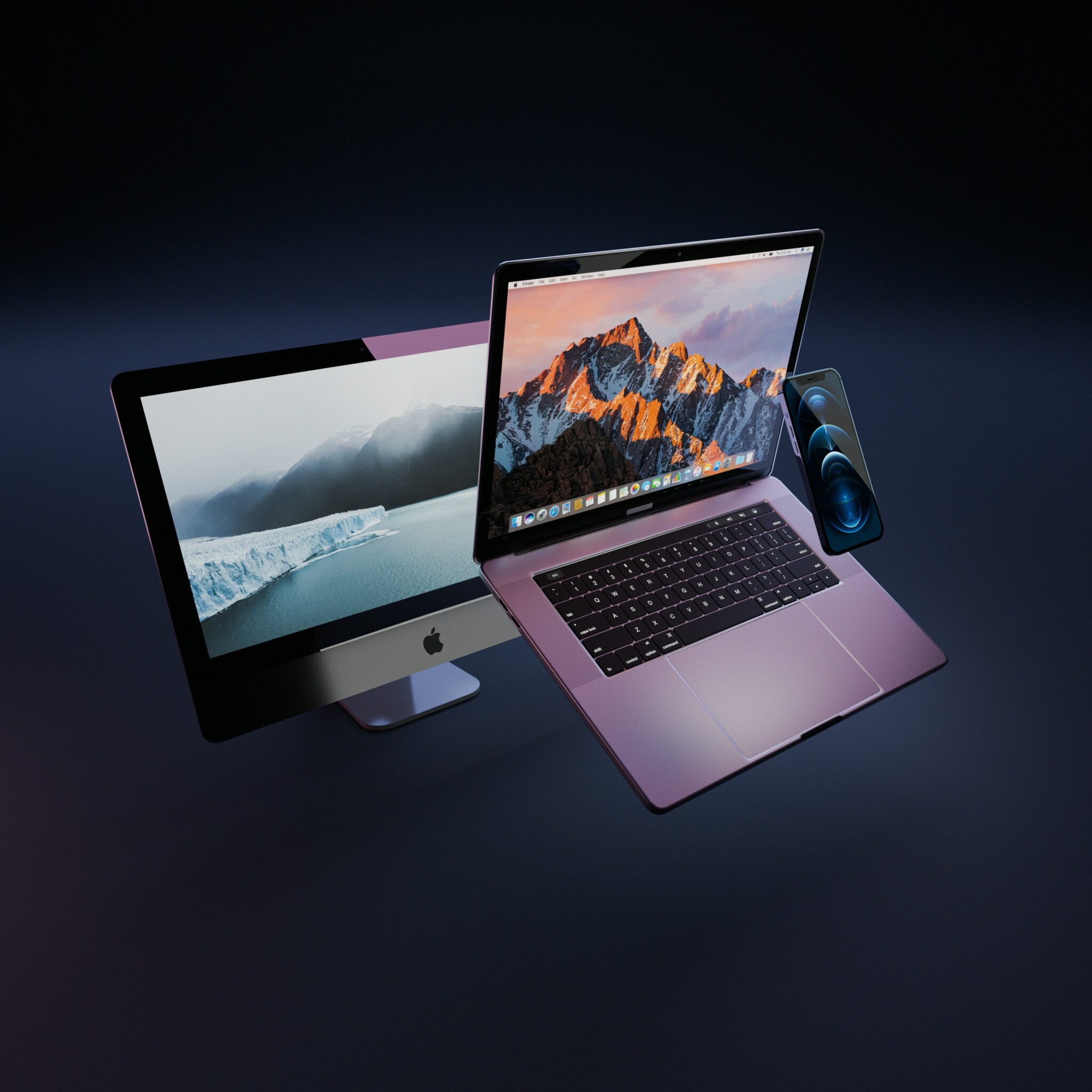 A close-up photo showcasing three Apple products: a MacBook Pro laptop, an iPhone, and an iMac desktop computer.