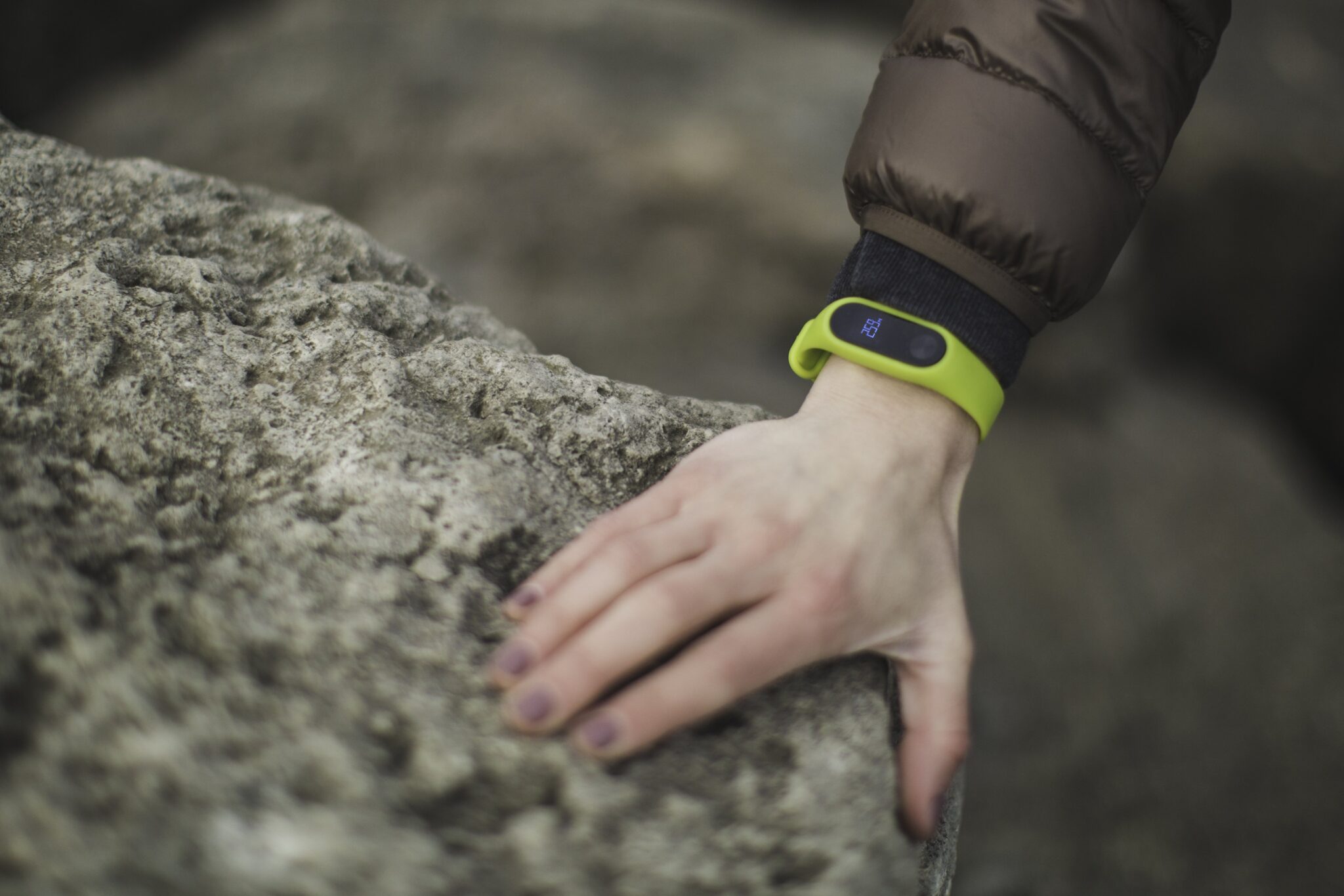 Person using a Fitbit smartwatch with their hand on a rock