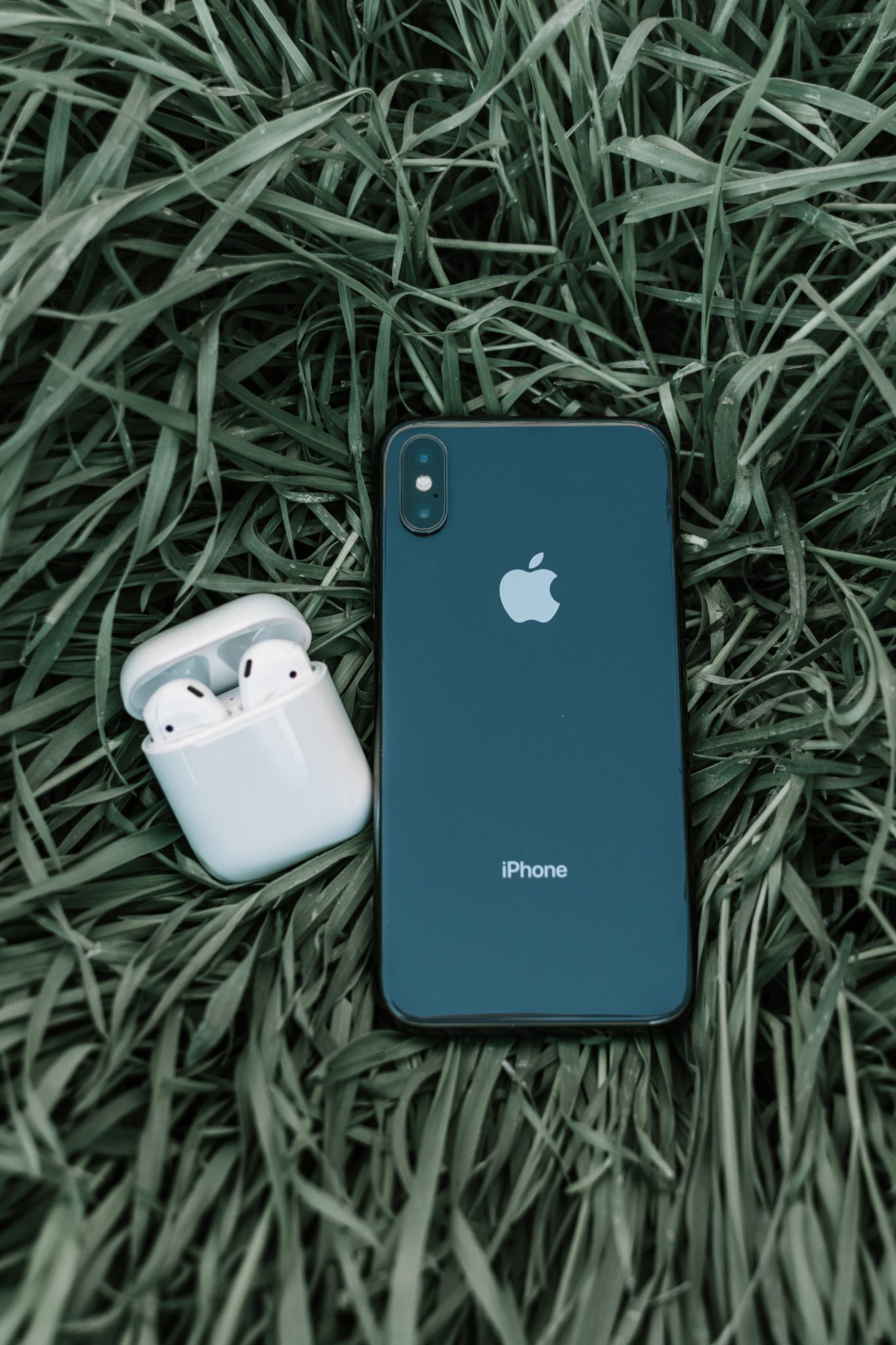 AirPods and iPhone on the grass representing green and circular economy